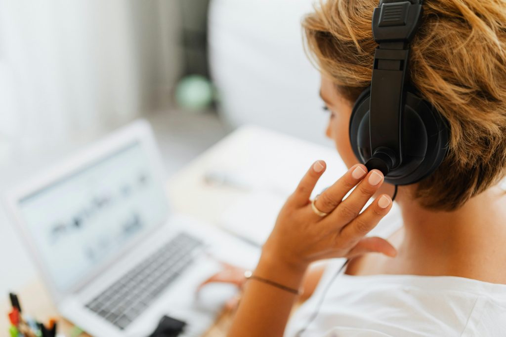 Woman at home using headphones and laptop for online work or video call.